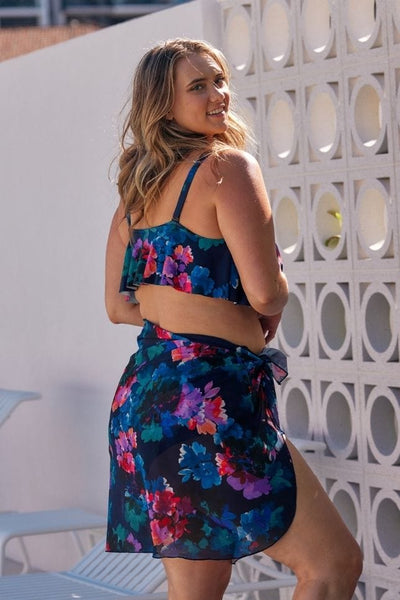 Back of curvy model wearing long mesh wrap skirt with tie detail in navy and pink floral print