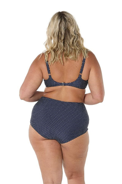 Back of model in studio wearing high waisted pant in navy white polkadot for curve women