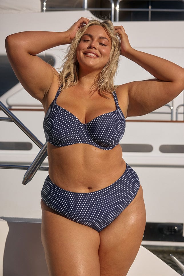 Front of model wearing high cut bikini pant in navy white polkadot for plus size women