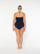 Woman wearing a black strapless swimsuit on a white background