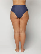 Woman wearing a blue polka dot bikini bottom on a plain background