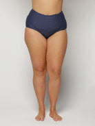 Navy blue polka dot high-waisted bikini bottom on a plain background