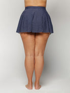 Navy polka dot skirt worn by a woman on a white background