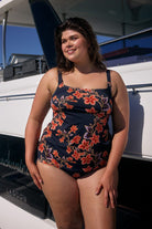 Brunette model wearing navy and orange multi coloured floral swim pant