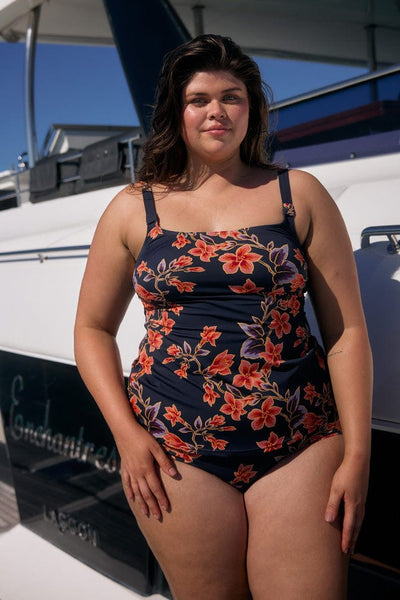 Brunette model wearing tankini top in navy and orange floral with scoop neckline