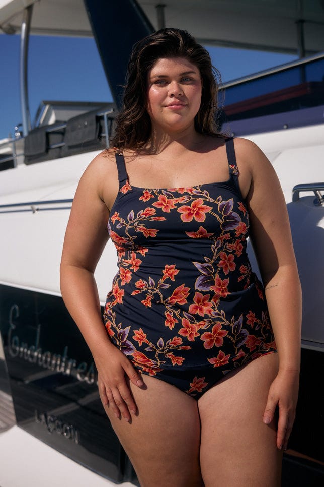 Brunette model wearing tankini top in navy and orange floral with scoop neckline