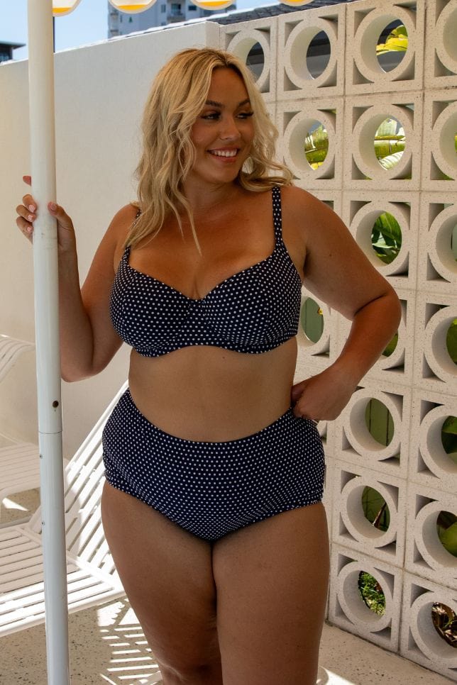 Blonde curve model by pool wearing flattering high waisted swim pant in navy and white spots