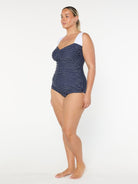 Woman wearing a navy patterned one-piece swimsuit on a white background