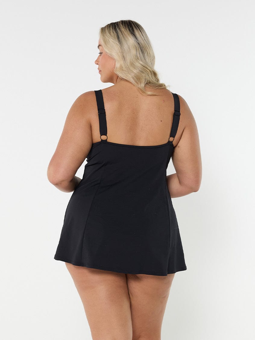 Back of woman in studio wearing short length swim dress in paisley print with adjustable straps