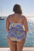 Back of model wearing pastel blue and yellow paisley high waisted swim bottoms for curve woman