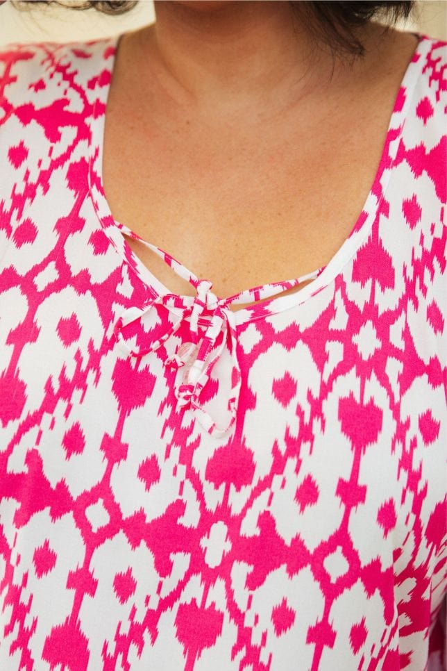 close up photo of model in the pink and white kaftan showing the tie detail at the front