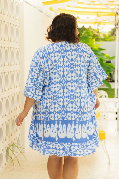back of plus size model wearing a cornflower blue block printed kaftan dress