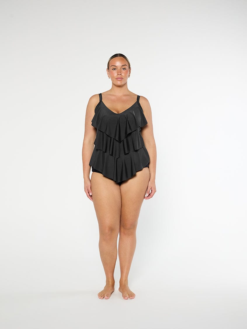 Woman wearing a black ruffled swimsuit on a white background