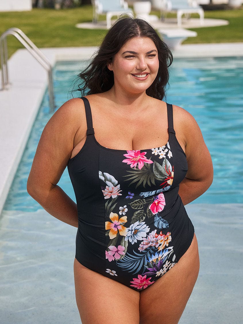 Brunette model wears chlorine resistant scoop neck black floral one piece