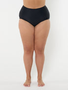 Person wearing black high-waisted bikini bottoms on a white background