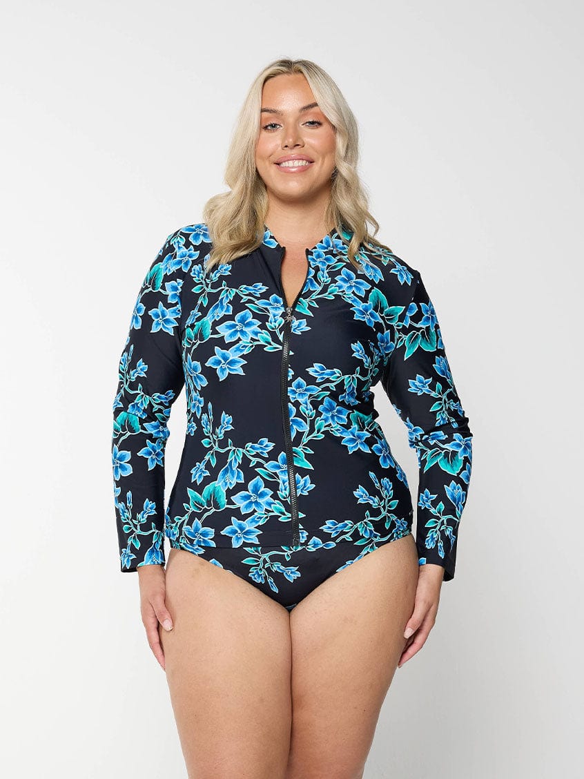 Blonde model shows blue floral rash vest with long sleeves and full zip
