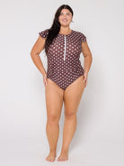 Woman wearing a brown polka dot swimsuit on a white background