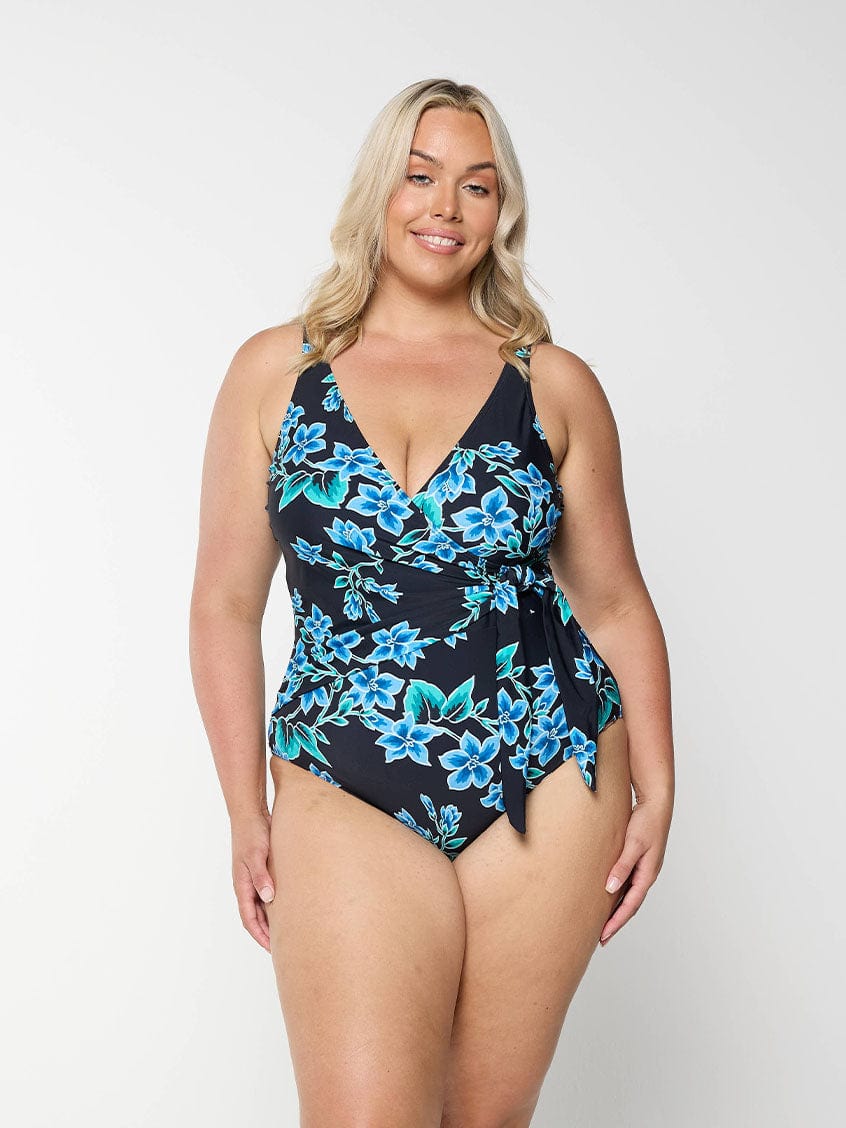 Blonde model wears plus size v neck crossover one piece in blue floral design