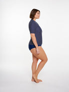 Woman wearing a navy blue patterned swimsuit on a white background