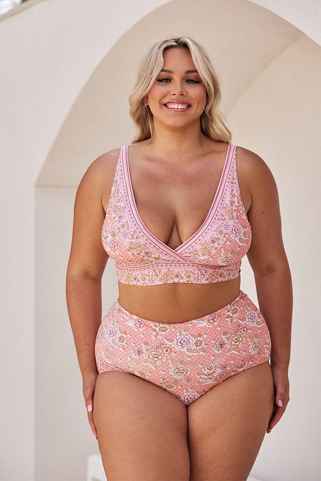 Blonde model wearing light pink floral bikini top and high waisted pant