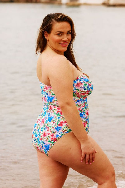 Side of model wearing plus size bandeau swimsuit with removable straps in floral print