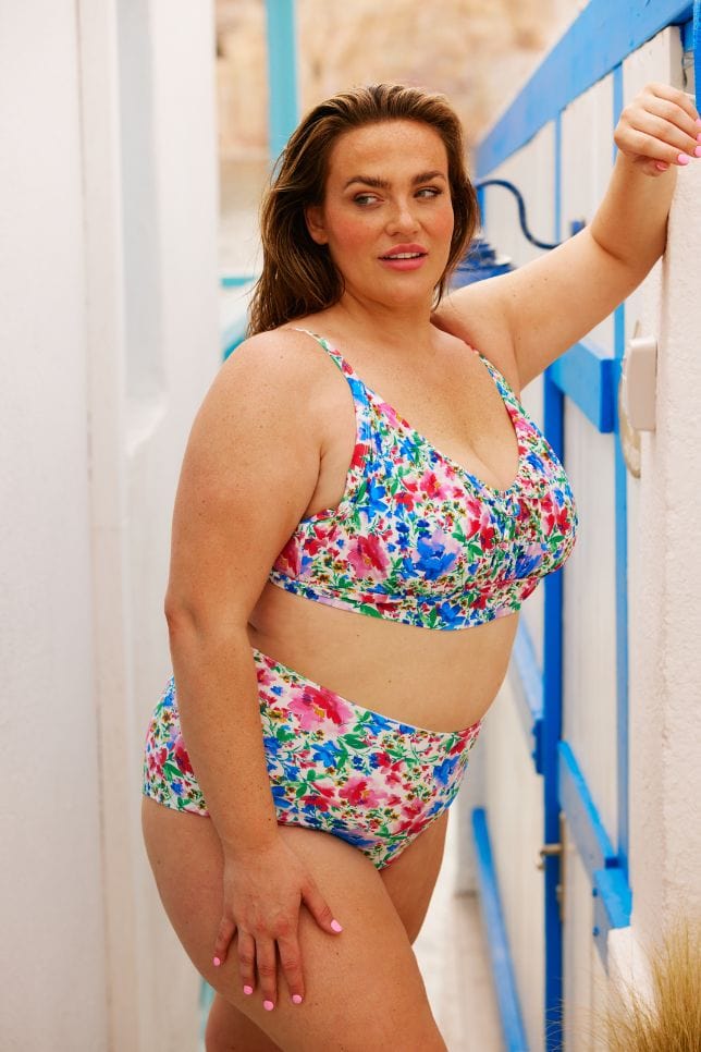 Plus size model wearing ruched bikini top in bright floral colours with tie detail