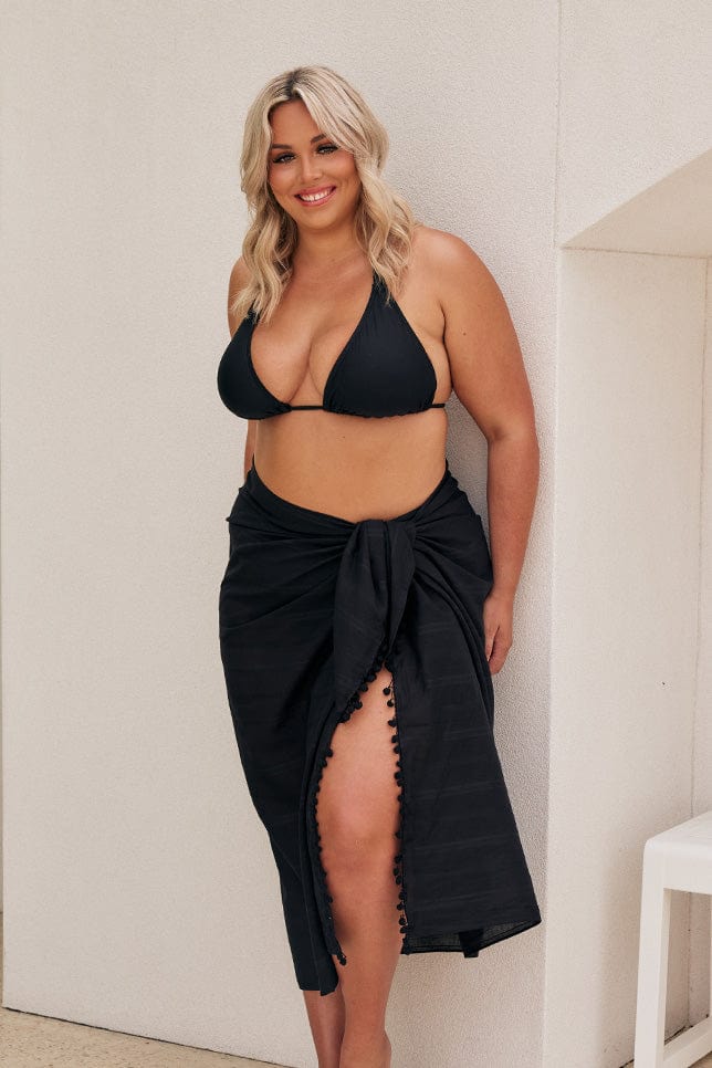 Model wearing black bikini with black sarong