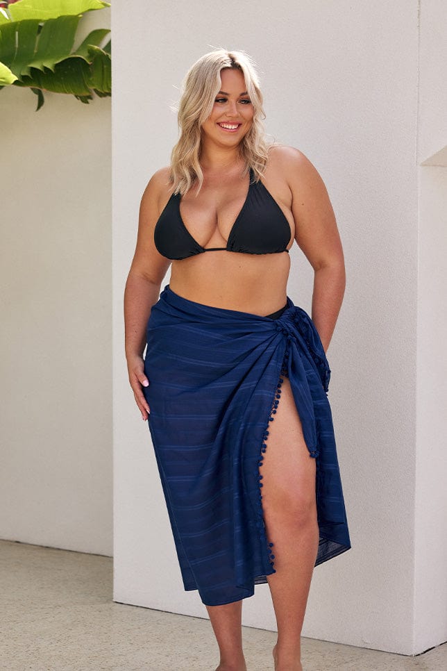 Blonde model wearing black bikini with navy sarong