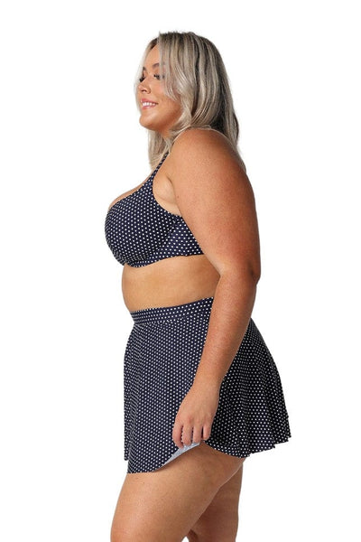 Side profile of blonde curve model wearing high waisted navy polkadot swim skirt
