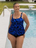 Woman wearing a blue and black patterned swimsuit by a pool