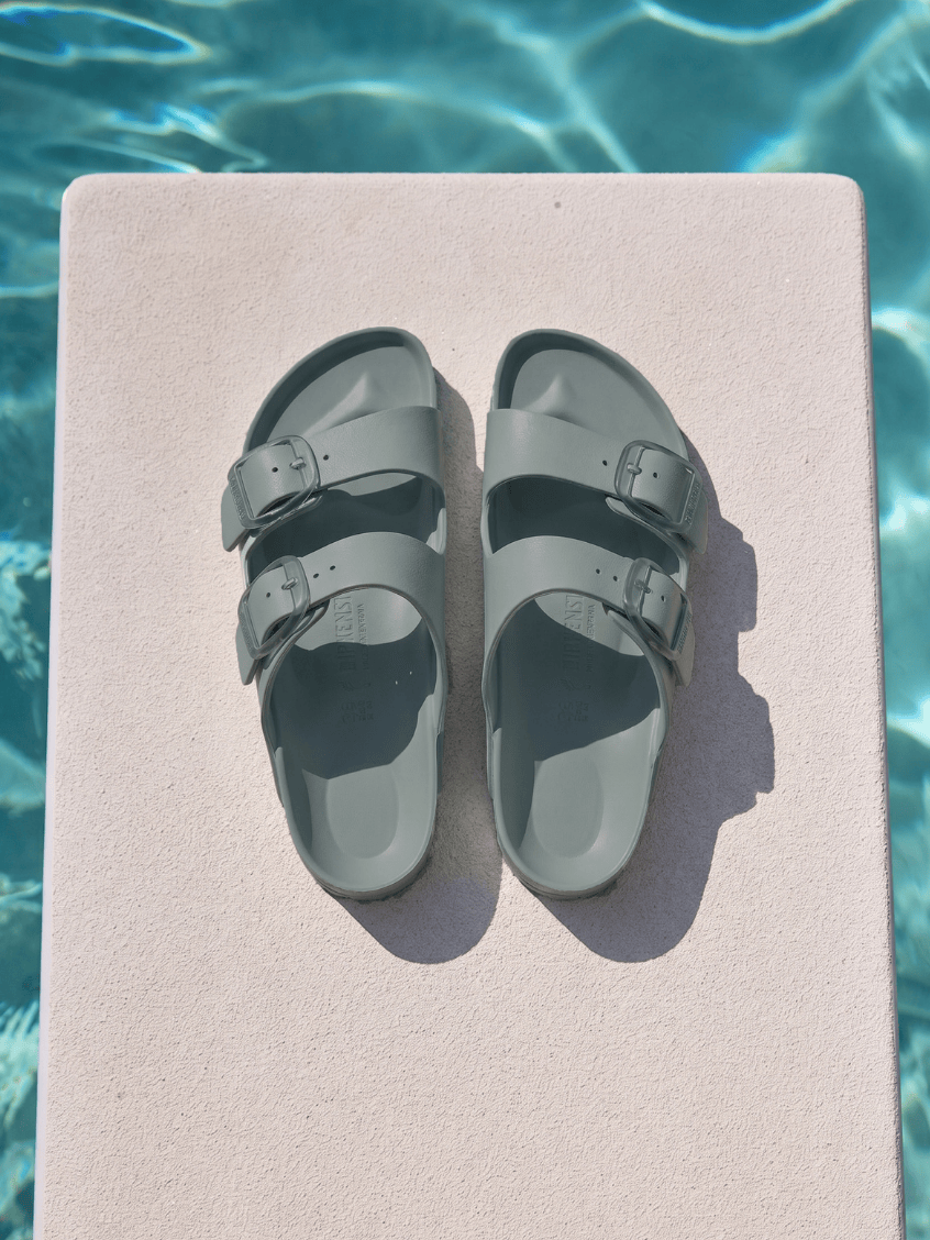 Sage birkenstock sitting on diving board by pool with two straps