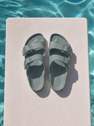Sage birkenstock sitting on diving board by pool with two straps