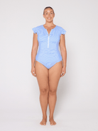 Woman wearing a light blue swimsuit with cap sleeves on a white background