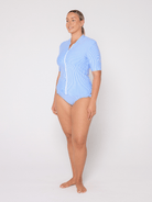 Woman wearing a light blue rash vest top with a white background