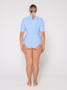 Person wearing a light blue rash vest on a white background