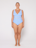 Woman wearing a blue v neck one piece swimsuit on a white background