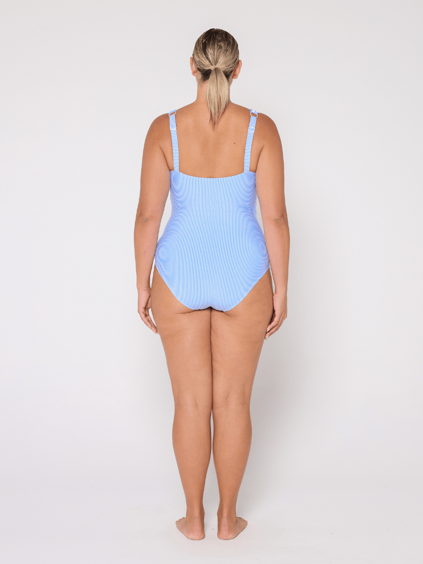 Woman wearing a light blue V neck swimsuit with adjustable straps on a white background