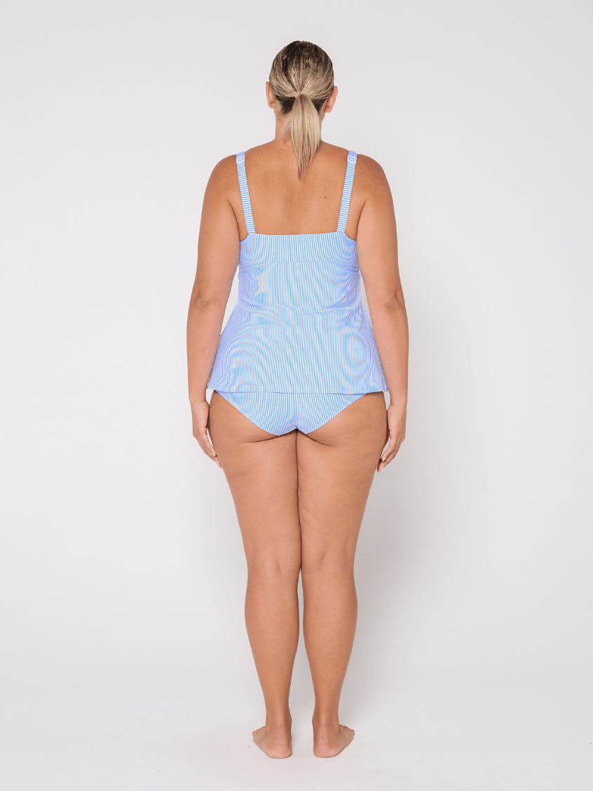 Woman wearing a light blue tankini swim top on a white background