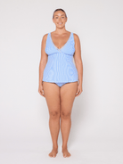 Woman wearing a light blue swimsuit against a white background