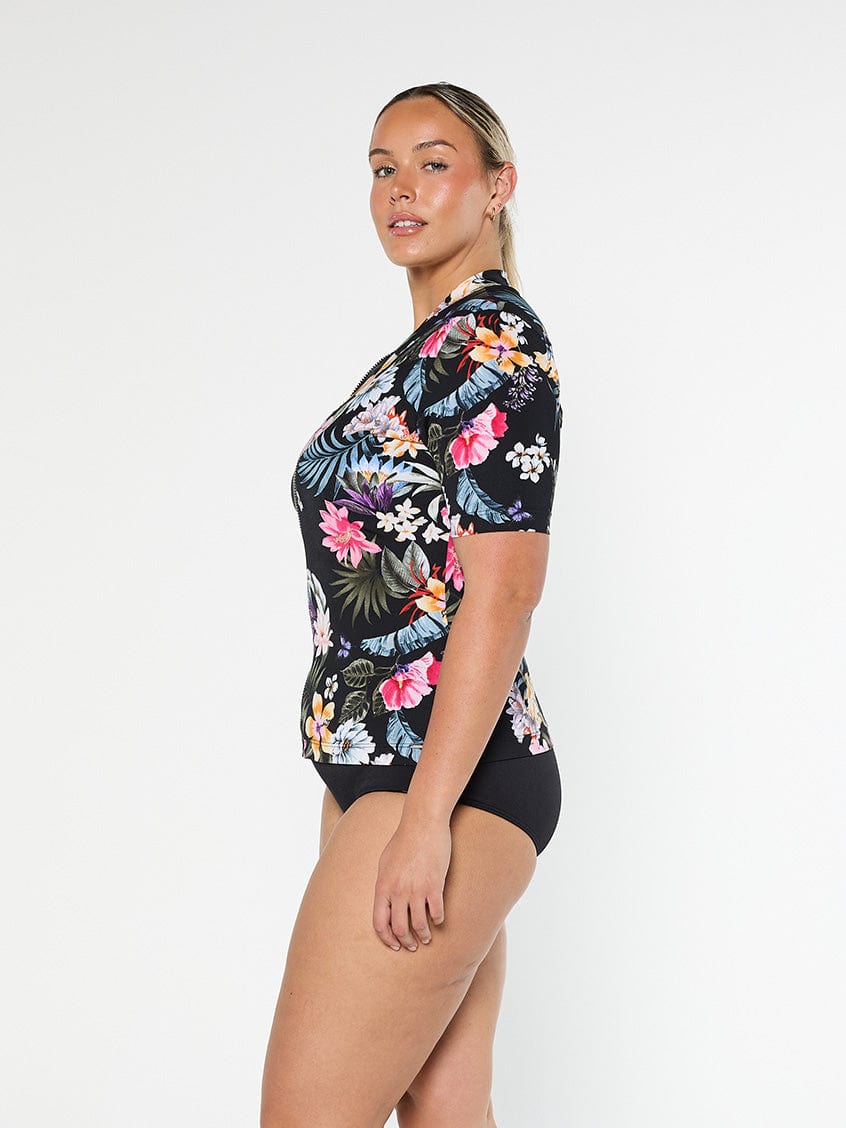 Blonde model shows the side of pool proof short sleeve rashie in black floral print