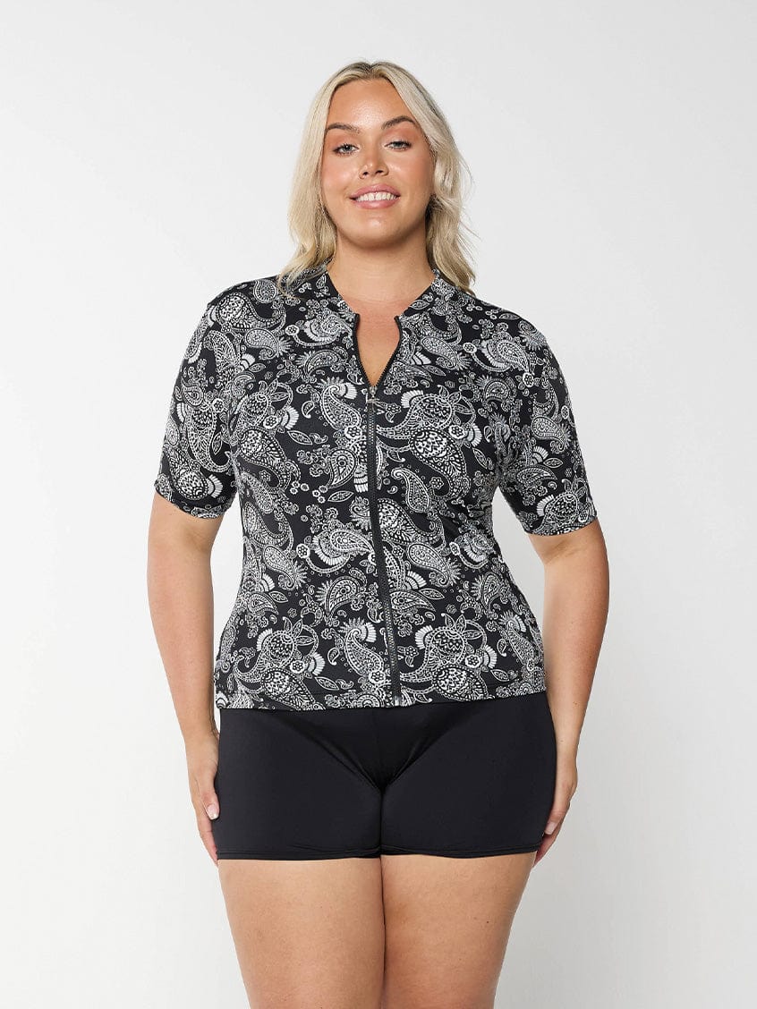 Front of blonde model in studio wearing plus size rash vest with zip front detail in paisley chlorine resistant