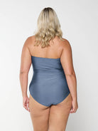 Back of blonde curve model in studio wearing a grey bandeau one piece with removable and adjustable straps