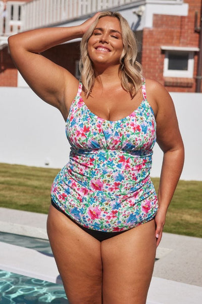 Blonde curve model next to pool wearing a underwire tankini top with ruching in bright coloured floral print