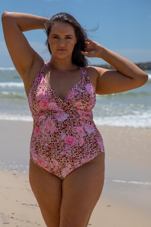 Model on Beach wearing a pink animal print swimsuit with pink flower pattern on it