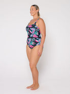 Woman wearing a colorful one-piece swimsuit with a white background