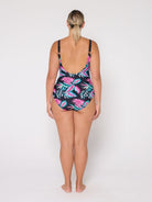 Woman wearing a tropical leaf patterned swimsuit with low socop back on a white background