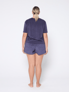 Person wearing a navy terry towelling t-shirt and shorts set on a white background