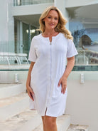 Front of model wearing a zip through terry towelling dress in white with pockets