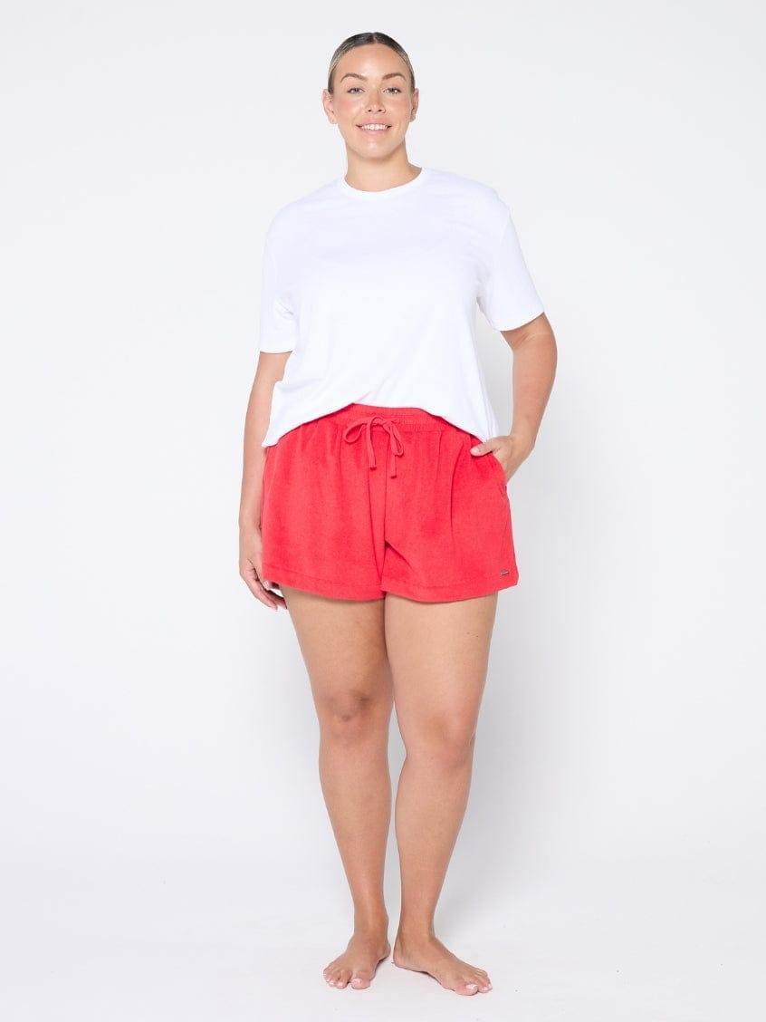 Person wearing red shorts and a white top on a white background
