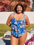 Brunette model wears flattering blue floral one piece with 3 tiers for tummy control